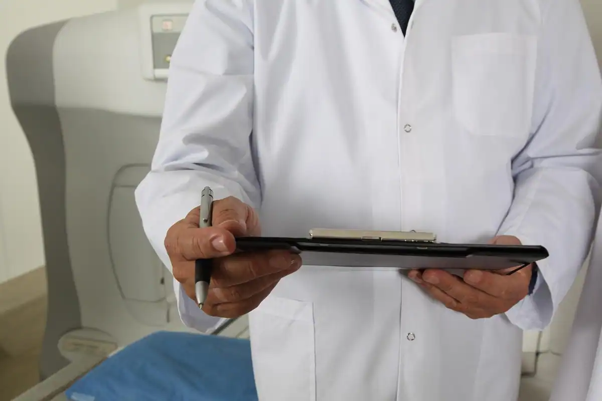 Medic în halat alb care notează pe un clipboard rezultatele analizelor unui pacient