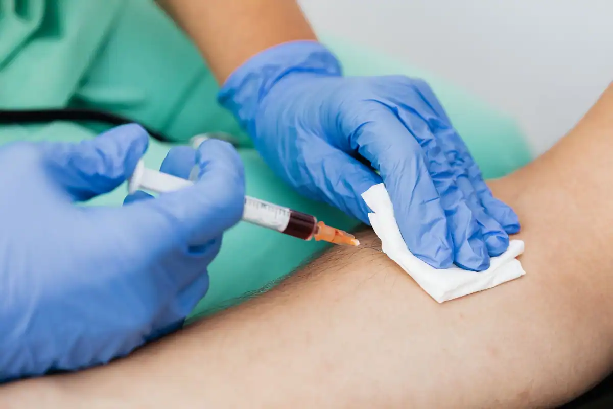Medic care recoltează sânge cu seringa de la un pacient, într-un cadru clinic