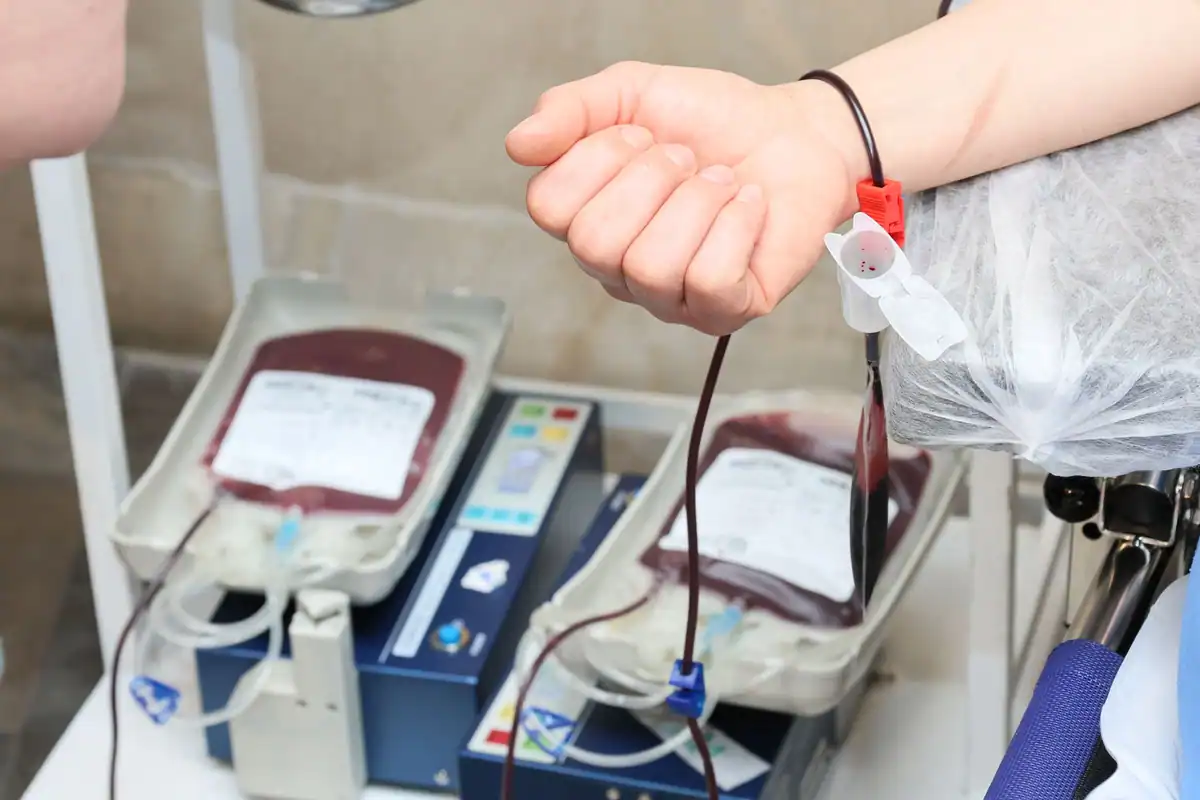 Brațul unui donator și pungi cu sânge într-un centru de donare
