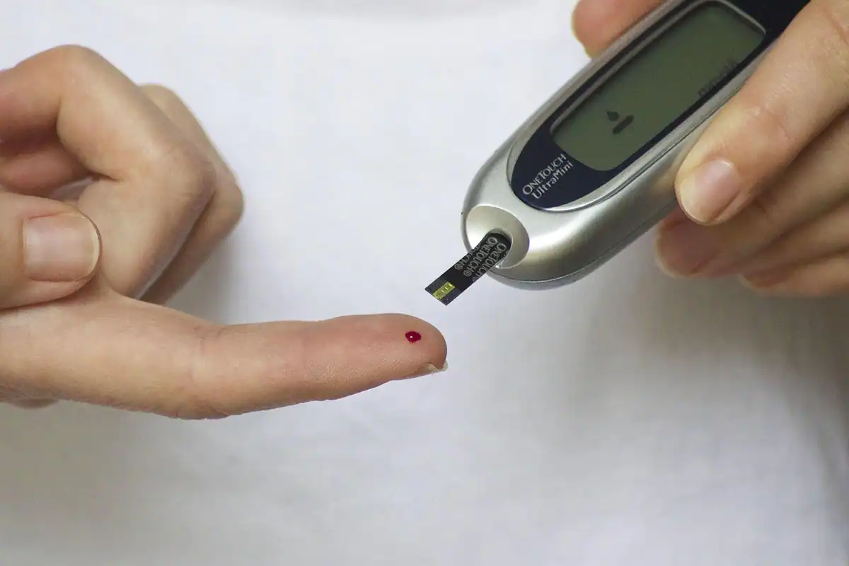 Glucometru și deget înțepat cu o picătură de sânge pentru măsurarea glicemiei