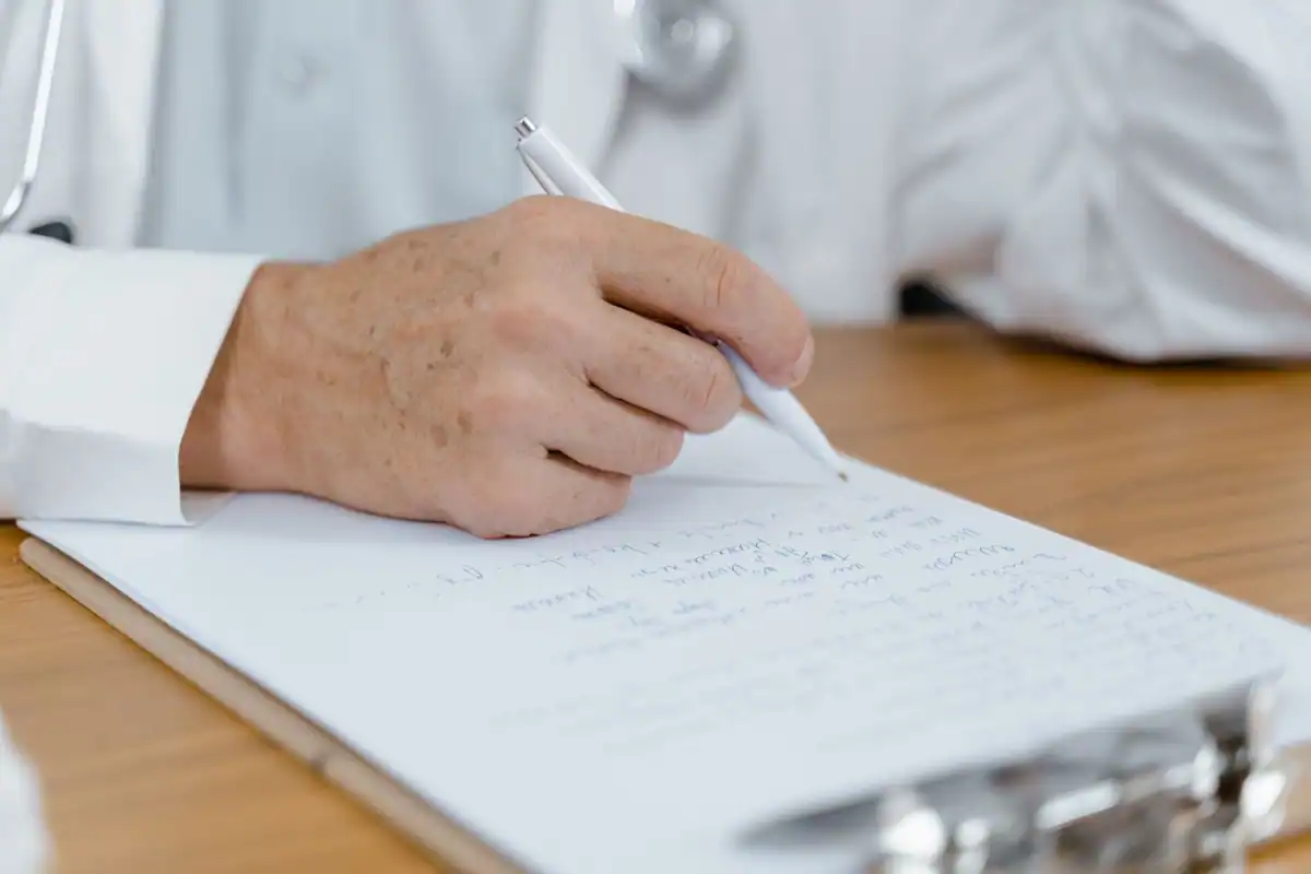 Caiet și pix pe biroul unui medic, pentru notarea întrebărilor după analize