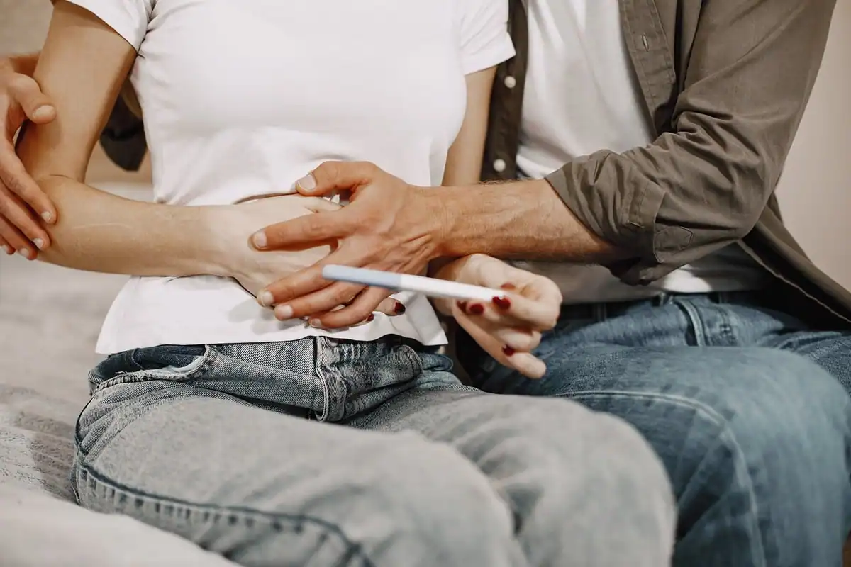 Cuplu care se ține de mână și privește rezultatul unui test rapid de sarcină